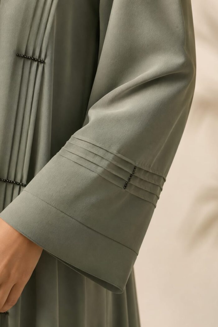 Lake green stone abaya close-up of pleated plates and bead stone detail