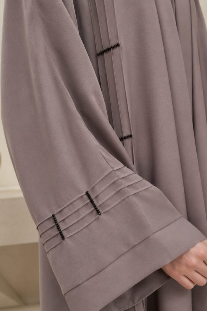Light grey stone abaya close-up of pleated plates and bead stone detail